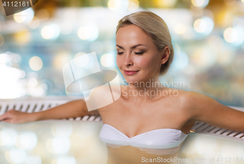 Image of happy woman sitting in jacuzzi at poolside