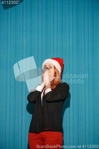 Image of Surprised christmas girl wearing a santa hat
