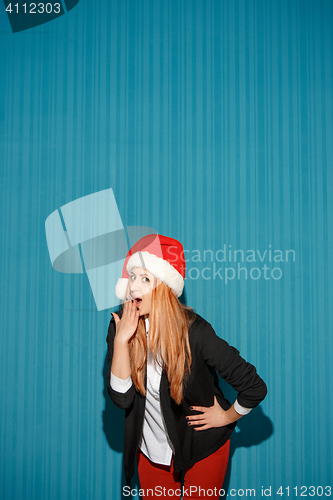 Image of Surprised christmas girl wearing a santa hat