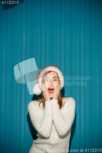 Image of Surprised christmas girl wearing a santa hat