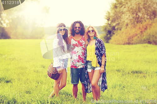 Image of smiling young hippie friends on green field