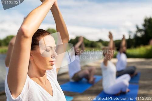 Image of people meditating in yoga lotus pose outdoors