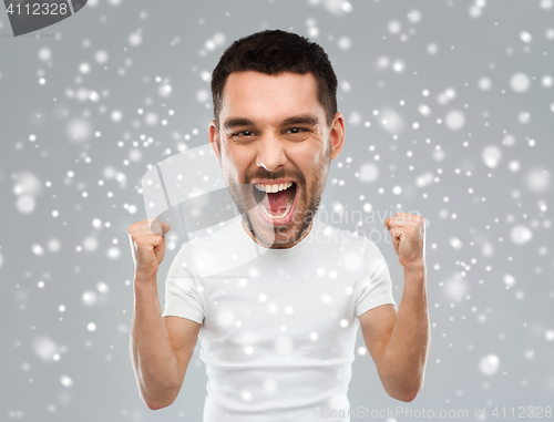 Image of angry young man celebrating victory over snow