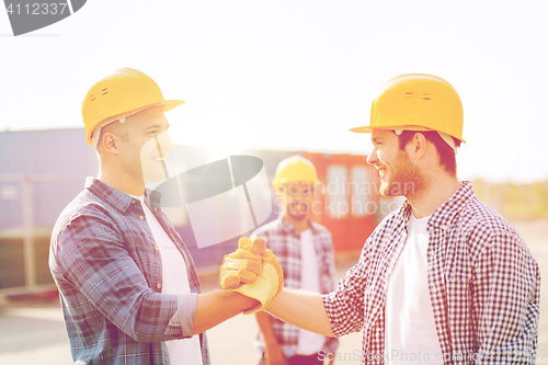 Image of group of smiling builders in hardhats outdoors