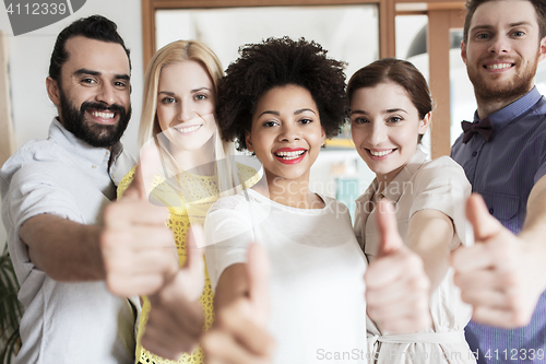 Image of happy creative team showing thumbs up in office