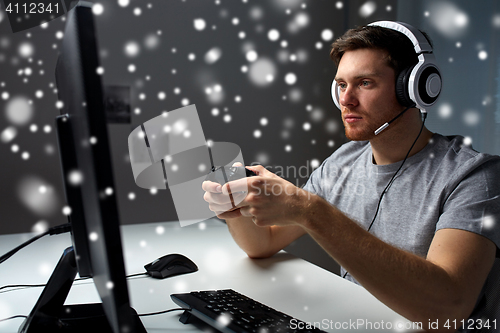 Image of man in headset playing computer video game at home