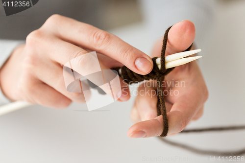 Image of close up of hands knitting with needles and yarn