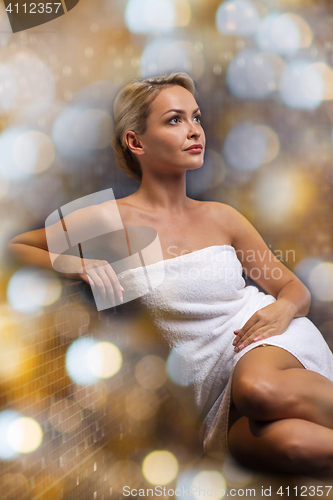 Image of beautiful young woman sitting in bath towel