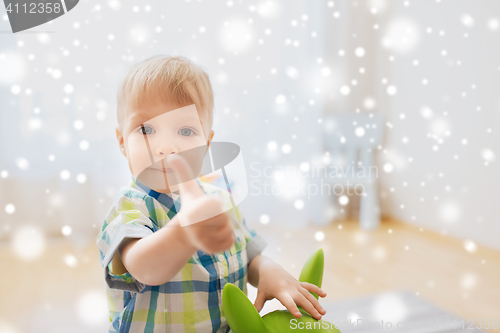 Image of happy baby boy playing with toy showing thumbs up