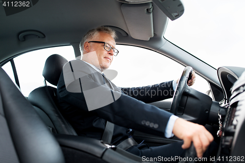 Image of happy senior businessman driving car