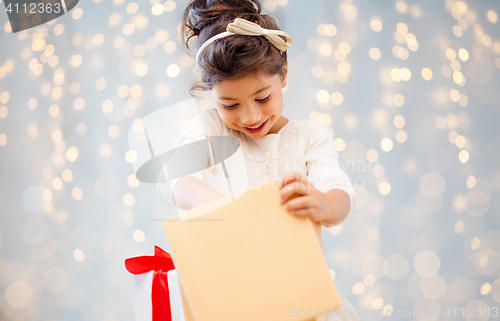 Image of smiling little girl opening gift box over lights