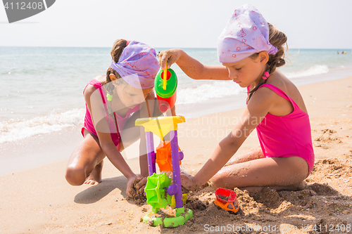 Image of Two children playing with toys in the sand on the sea beach