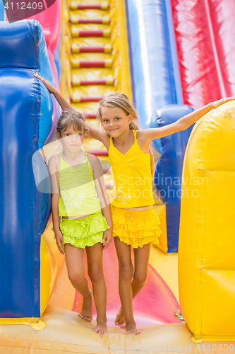 Image of Two children stand at the entrance of a large inflatable trampoline