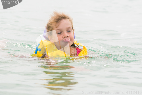 Image of Five-year girl stuck out her tongue with pleasure swimming in the sea