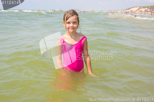 Image of The girl in the pink bathing suit standing in the water of the sea