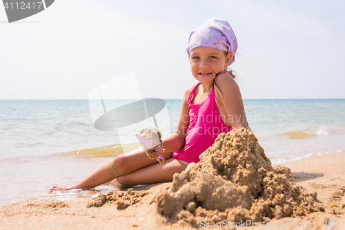 Image of The baby digs a shovel sand sitting on the beach