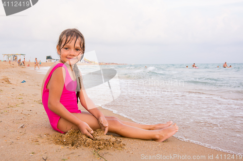 Image of Five-year girl sitting on the beach seaside