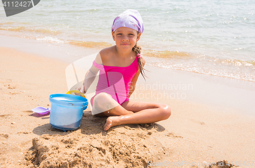 Image of A child plays in the sand shovel and bucket on the sea shore