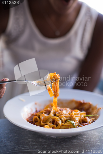 Image of a young African American woman eating pasta