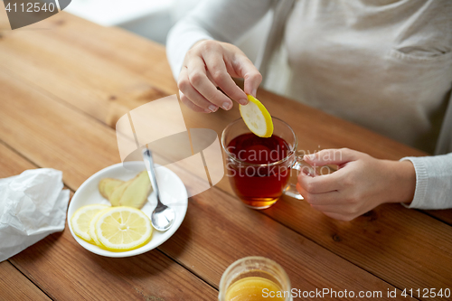 Image of close up of woman adding lemon to tea cup