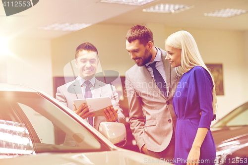 Image of happy couple with car dealer in auto show or salon