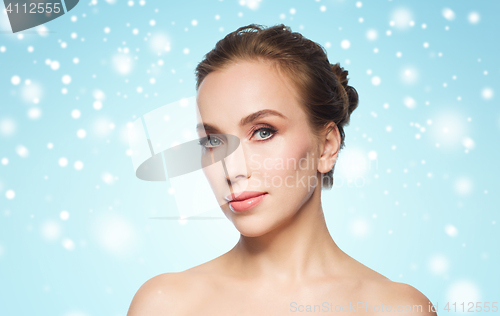 Image of beautiful woman face over blue background and snow