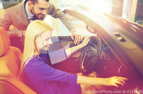 Image of happy couple buying car in auto show or salon