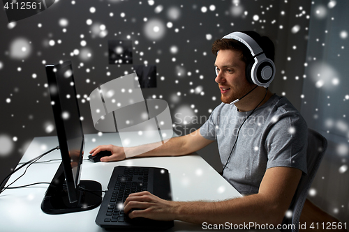 Image of man in headset playing computer video game at home