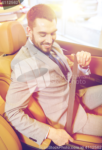 Image of happy man sitting in car at auto show or salon