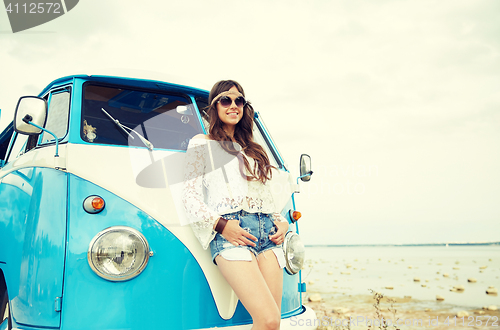 Image of smiling young hippie woman with minivan car