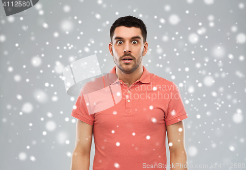 Image of surprised man in polo t-shirt over snow background