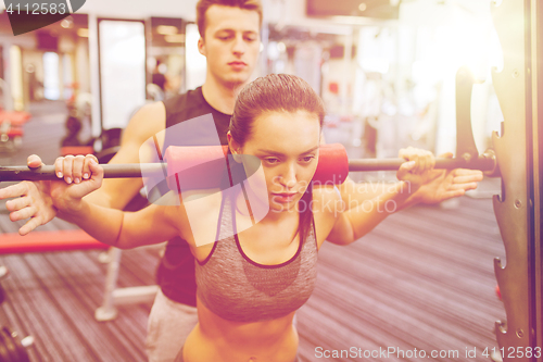 Image of man and woman with barbell flexing muscles in gym