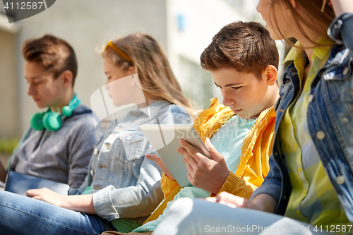 Image of friends or students with tablet pc outdoors