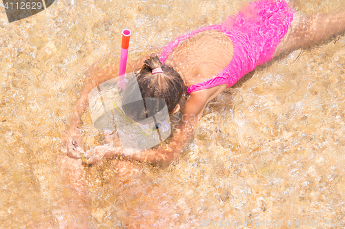 Image of Girl in the mask and tube swims under water in shallow water