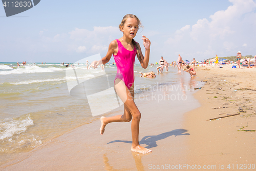 Image of Seven-year girl runs on the beach from the sea