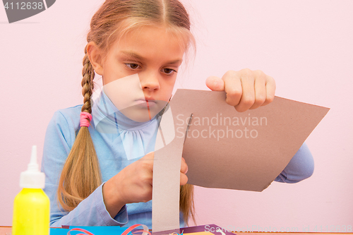 Image of The child cuts a strip of cardboard in the classroom