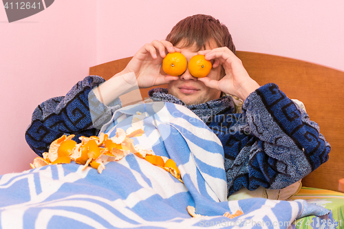 Image of Man lying in bed and funny tangerines closed eyes
