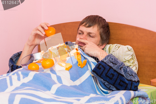 Image of A man who lies in bed sick of mandarins