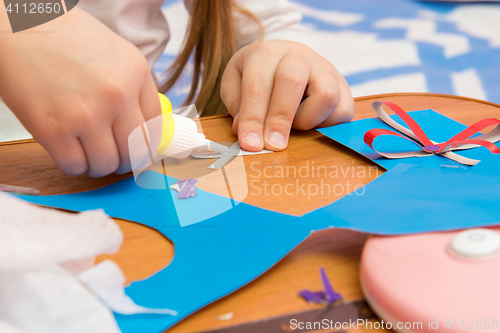 Image of Girl sticks two strips, making crafts out of colored paper