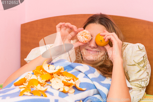 Image of Happy funny woman put tangerines to eyes