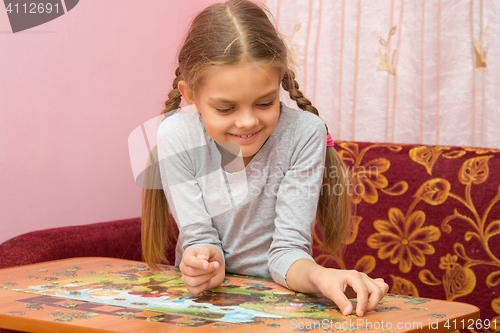 Image of Girl collects a picture from puzzles