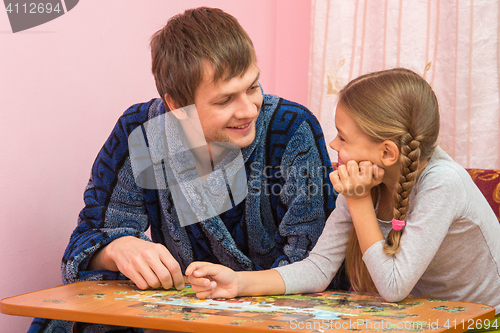 Image of Father and daughter looked at each other collecting puzzle elements