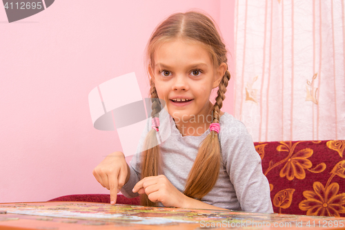 Image of Girl collects a picture of the puzzle, and looked into the frame