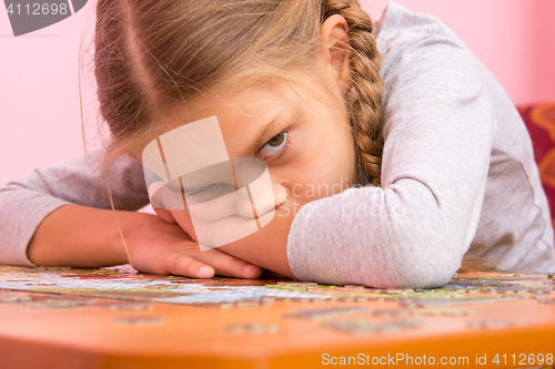 Image of The girl was very tired assemble a picture from puzzles