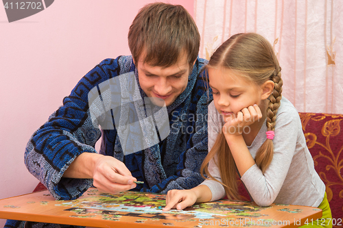 Image of Dad and daughter enthusiastically collect picture of puzzles