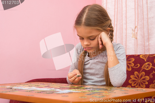 Image of The girl does not know where to put the next puzzle element