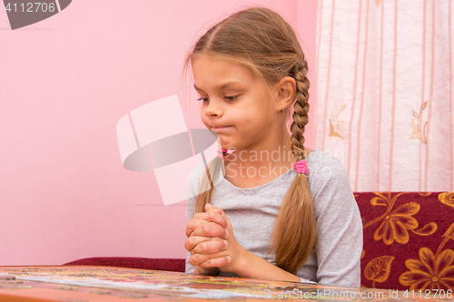 Image of Girl funny thought pouting cheeks collecting picture of puzzles