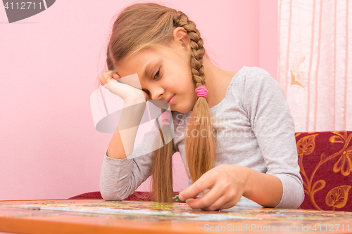 Image of Girl little tired collecting picture of puzzles