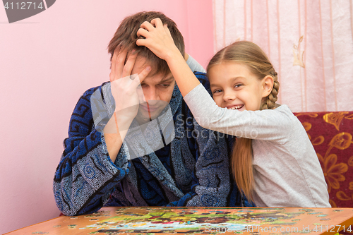 Image of Daughter fun soothes tired dad who collect puzzles