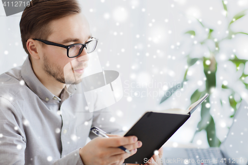 Image of creative male worker with book at home office